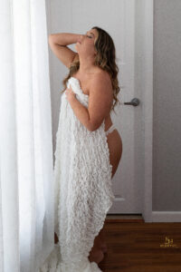 Curvy woman in Orlando boudoir studio wrapped in a white sheet.